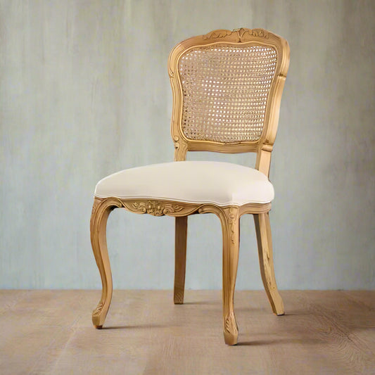 Decorative wooden chair with a wicker backrest and cream cushion against a white brick wall.