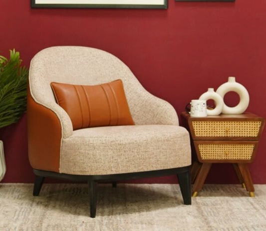 Beige armchair with orange cushion next to a wooden side table against a red wall.