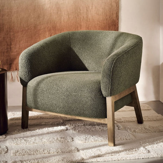 Green armchair in a room with a textured wall and rug.