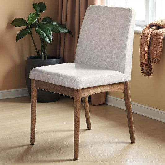 Chair with wooden legs and gray cushioned seat in a room with a plant and window.