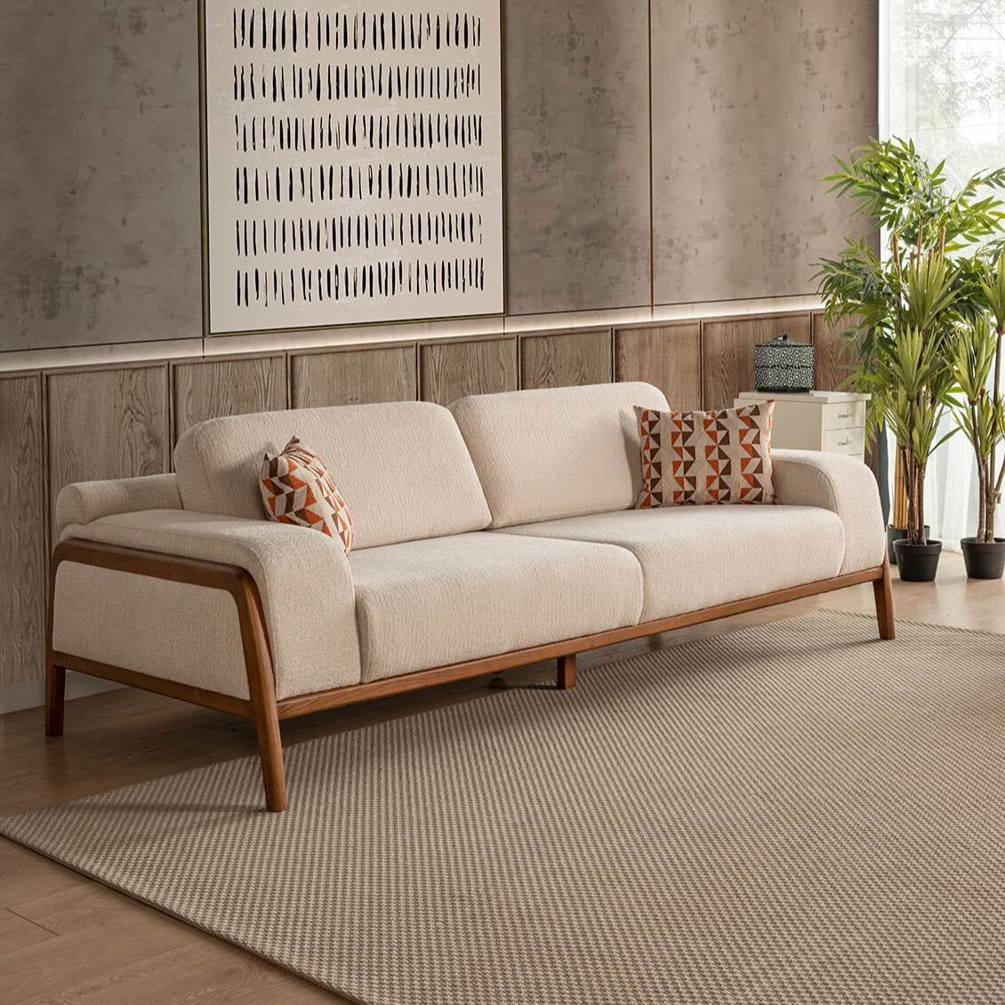 Beige sofa with wooden frame in a room with decorative wall art and plants.