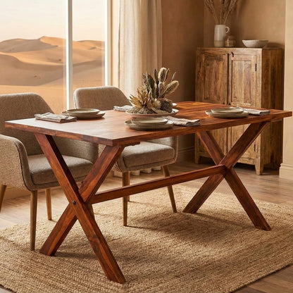 Wooden dining table with chairs in a room with a desert view through large windows.