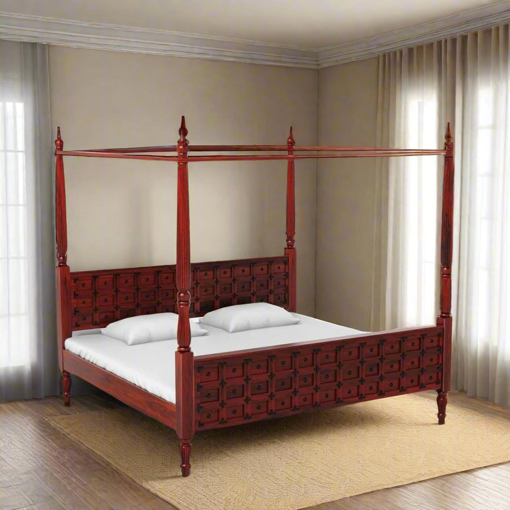 Red four-poster bed in a room with plants and artwork on the wall.