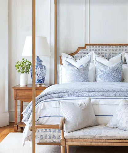 Bedroom with a four-poster bed and matching bench, featuring decorative pillows and lamps.