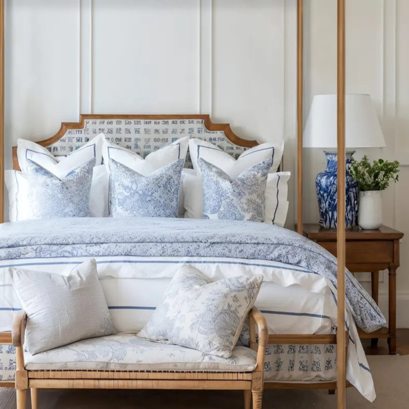 Bedroom with a four-poster bed and matching bench, featuring decorative pillows and lamps.