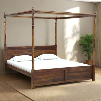 Wooden canopy bed with white bedding against a plain wall.