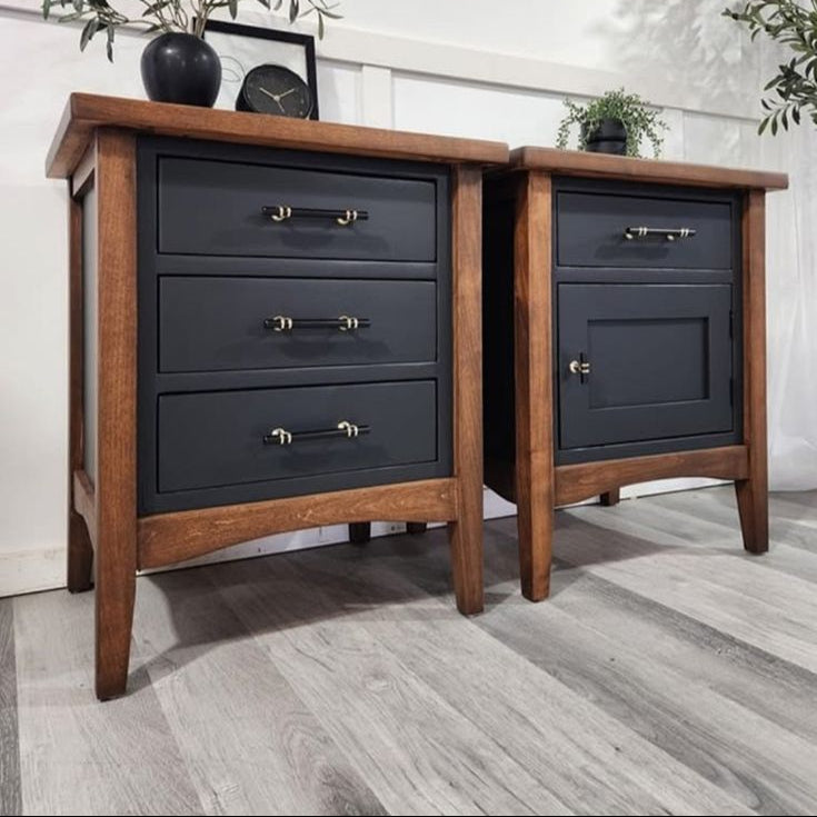 Pair of wooden nightstands with dark gray drawers and gold handles in a room setting.