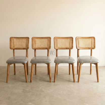 Four wooden chairs with wicker backrests and gray seats on a beige floor.