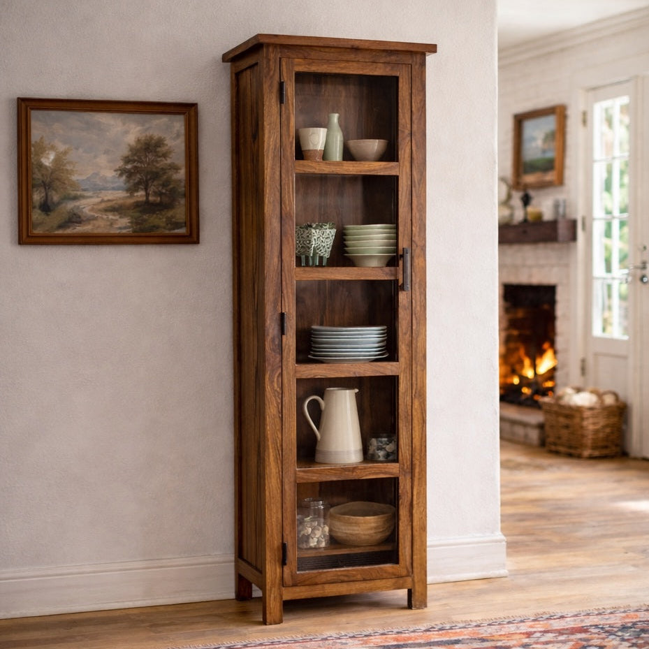 Tall wooden bookshelf in a room with a fireplace and framed picture on the wall.